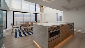 A modern kitchen with a large island, built-in oven, and a dining area with a view. - Newly renovated luxury retreat with incredible views, features 6 bedrooms and 5 baths! (Ocean City)
