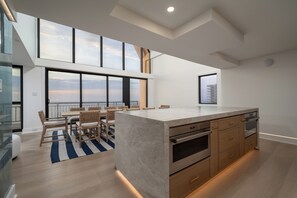 A modern kitchen with a large island, built-in oven, and a dining area with a view. - Newly renovated luxury retreat with incredible views, features 6 bedrooms and 5 baths! (Ocean City)