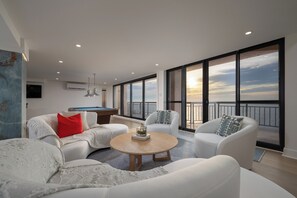 A modern living room with a pool table, large windows, and a view of the sky. - Newly renovated luxury retreat with incredible views, features 6 bedrooms and 5 baths! (Ocean City)