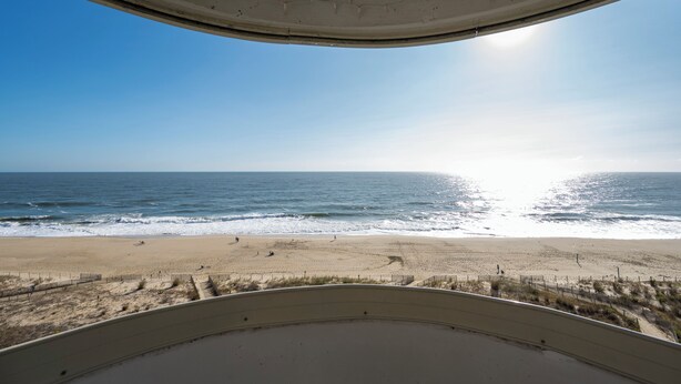 Vista de la playa desde un área techada, con una playa de arena y el océano al fondo.
