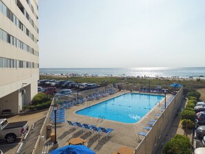 Ein Schwimmbecken mit Liegestühlen und Blick auf den Strand.