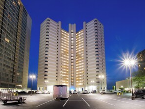 Un immeuble de grande hauteur, avec de nombreux étages, un parking à l’avant et une remorque au premier plan.