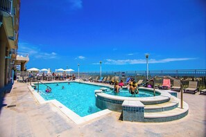 Ein Poolbereich mit Whirlpool, Liegestühlen und Sonnenschirmen.