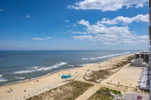 A beach with a clear sky, a sandy shore, and a few buildings in the background. - Three bedroom oceanfront condo in the luxurious Gateway Grand! (Ocean City)