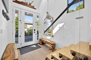 A modern interior with a staircase, a wooden bench, a mirror, and a door leading outside. - Artist Haven This custom contemporary home showcases the best of Bodega Bay! (Bodega Bay)
