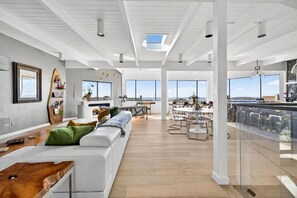 A spacious living area with a large white sofa, a wooden coffee table, and a dining area with a high table and chairs. - Artist Haven This custom contemporary home showcases the best of Bodega Bay! (Bodega Bay)