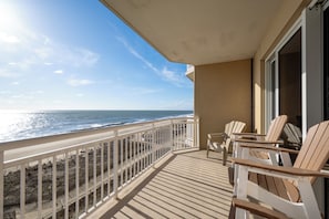 Ein Balkon mit Meerblick, Holzstühle und ein kleiner Tisch.