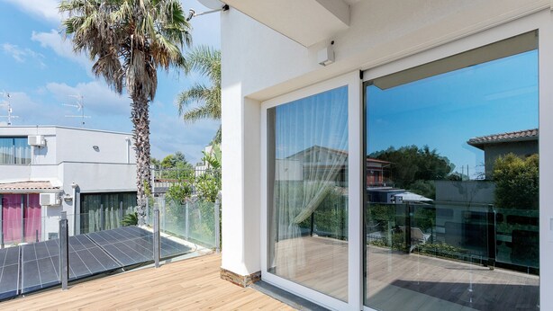 Ein moderner Balkon mit Holzboden, Glasfenstern und Solaranlage.