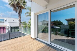 A modern balcony with a wooden floor, glass doors, and solar panels. - Villa Gloria Maria: Pool, Relaxation, Silence, Nature (Mascalucia)