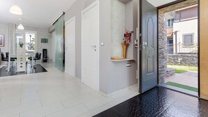 Ein modernes Interieur mit Essbereich, einem zur Tür hin führenden Flur und einem kleinen Außenbereich, der durch die Tür sichtbar ist.