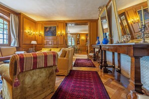 A traditional room with a wooden floor, a sofa, a dining table, and a large mirror. - Villa Goffrey, Sicily (San Ciro - Ulmi - Filci)