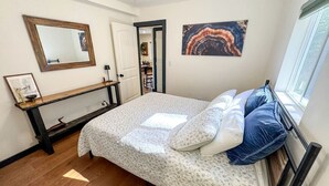 A bedroom with a bed, a bedside table, a mirror, and a painting on the wall. - Rustic Retreat with Private Pond, Gazebo & Creek in Andes, New York (Andes)
