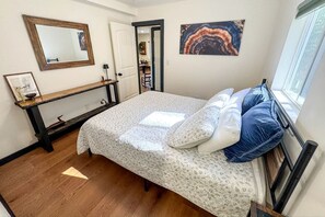 Ein Schlafzimmer mit einem Bett, einem Nachttisch, einem Spiegel und einem Bild an der Wand.