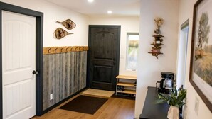 A hallway with a wooden floor, a white door, a dark wooden door, and a small table with a plant. - Rustic Retreat with Private Pond, Gazebo & Creek in Andes, New York (Andes)