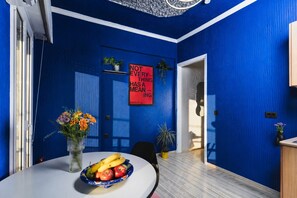 Ein Zimmer mit blauen Wänden, einer weißen Tür, einem roten Schild und einer Obstschale auf einem Tisch.