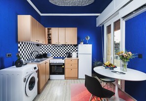 Une cuisine compacte avec des meubles en bois, un dosseret à carreaux, un lave-linge et un coin repas comprenant une table et des chaises.