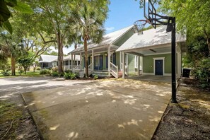 Ein Wohnhaus mit überdachter Veranda, Basketballkorb und grüner Tür.