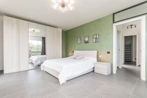 Ein modernes Schlafzimmer mit einem großen Bett, Nachttischen, einem Spiegel und Bildern an der Wand.