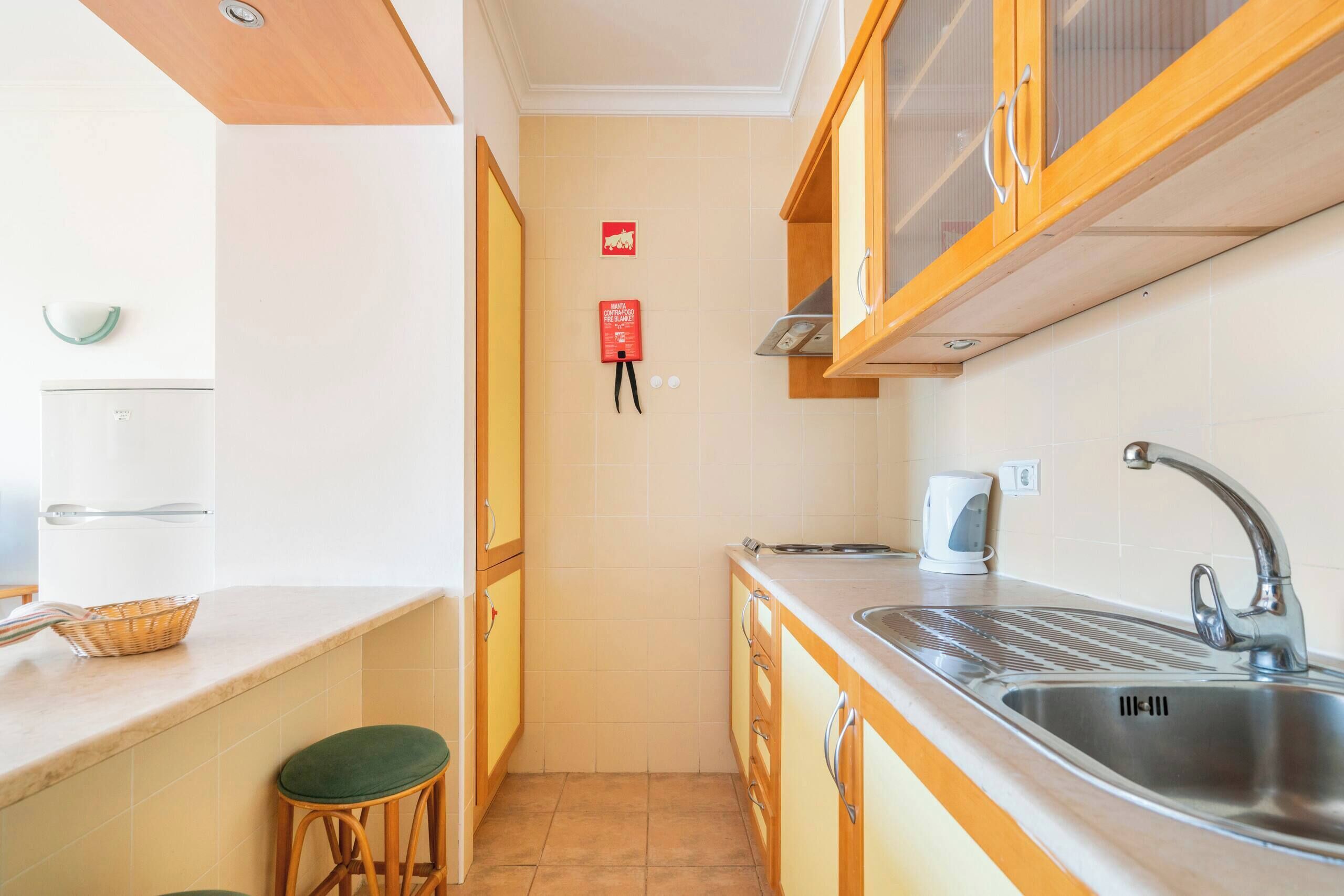 Cocina compacta con lavamanos, hervidor y extintor.