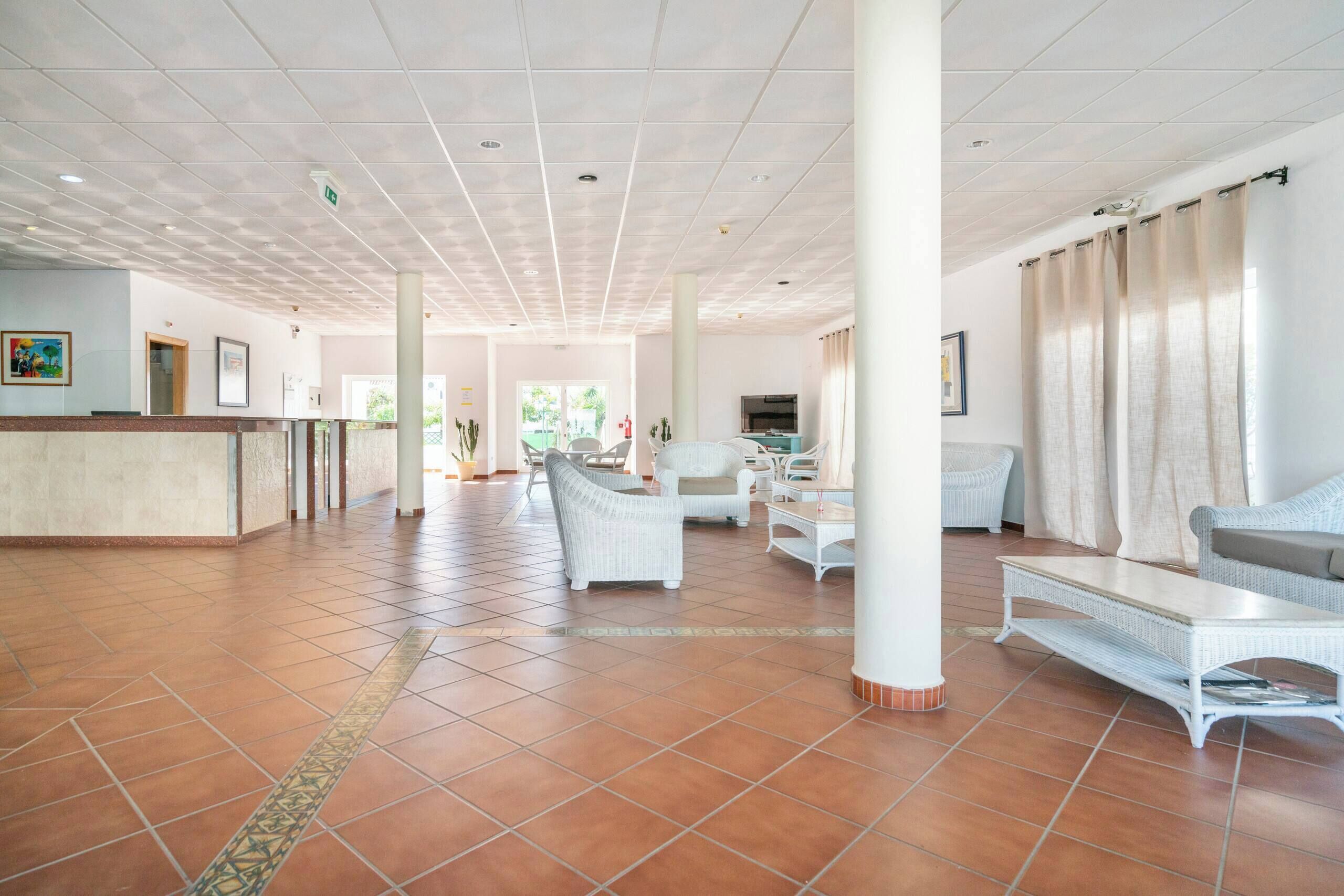 A spacious lobby with a reception desk, seating area, and a large window.