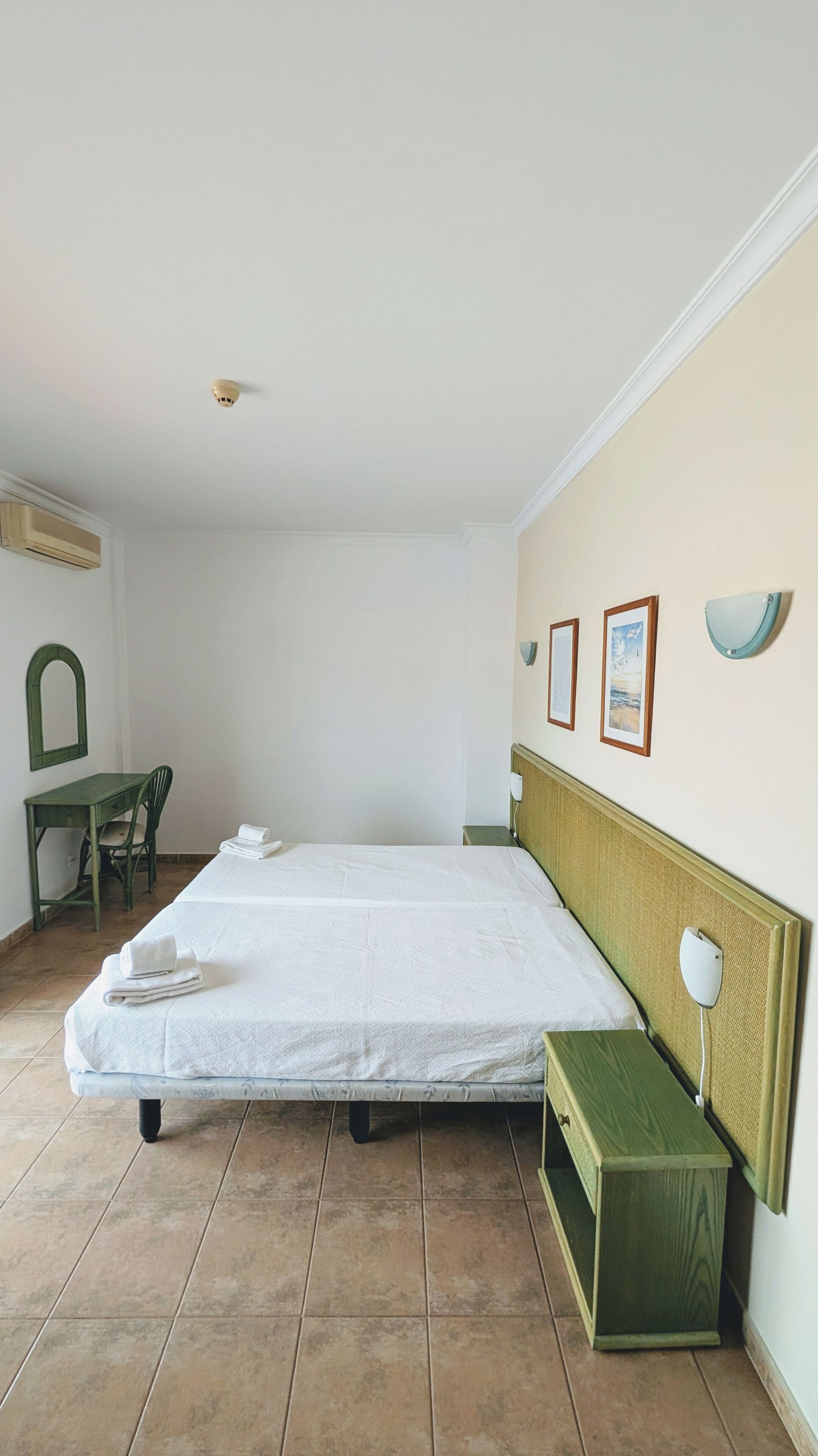 Une pièce comprenant un lit, un bureau, une chaise, une lampe fixée au mur et un cadre photo.