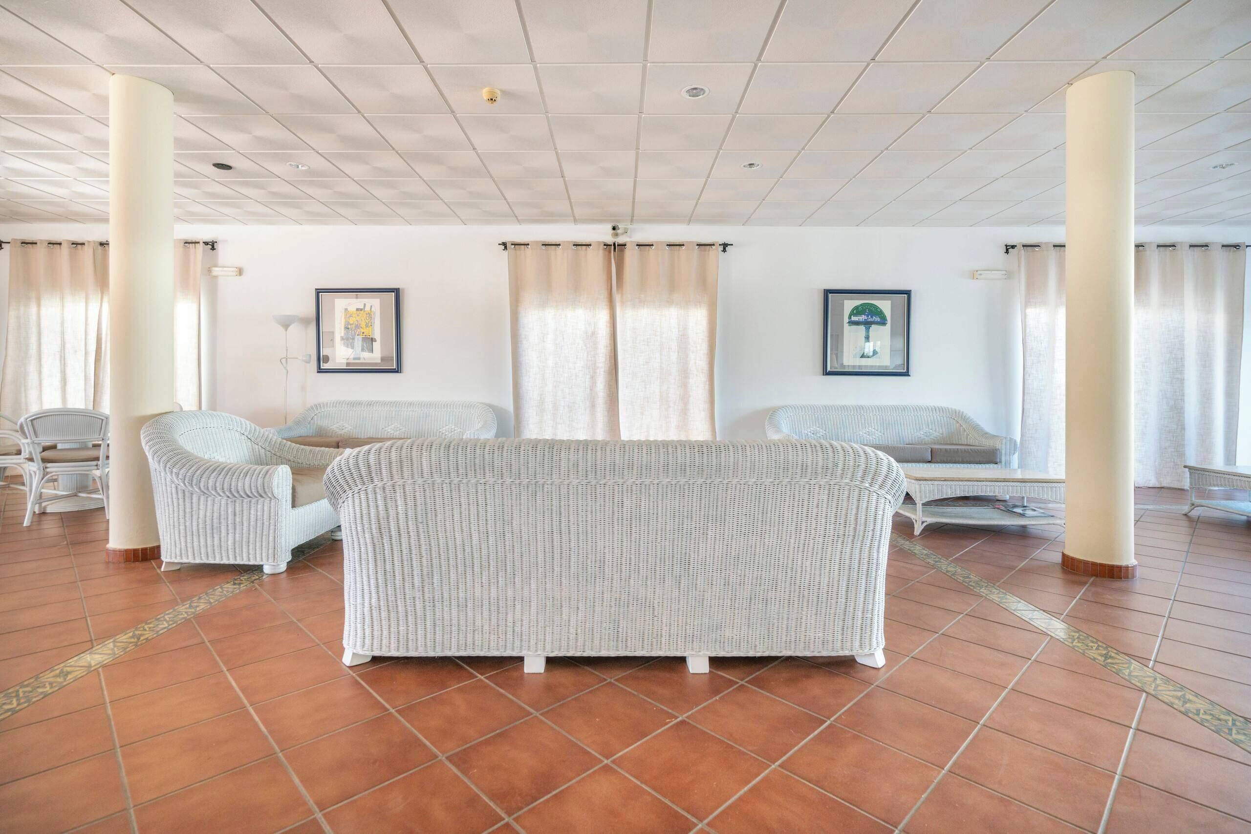 Una habitación amplia con un sofá grande, dos sillones, una mesita y un adorno en la pared.