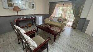 A living room with a sofa, a wooden chair, a coffee table, and a television.