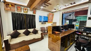 A modern living room with a sofa, a wooden desk, a television, and a computer. - Shree Villa Guest House (Varanasi)