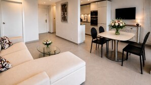 Ein modernes Wohnzimmer mit einer Couch, einem Glastisch und einem Essbereich mit Tisch und Stühlen.