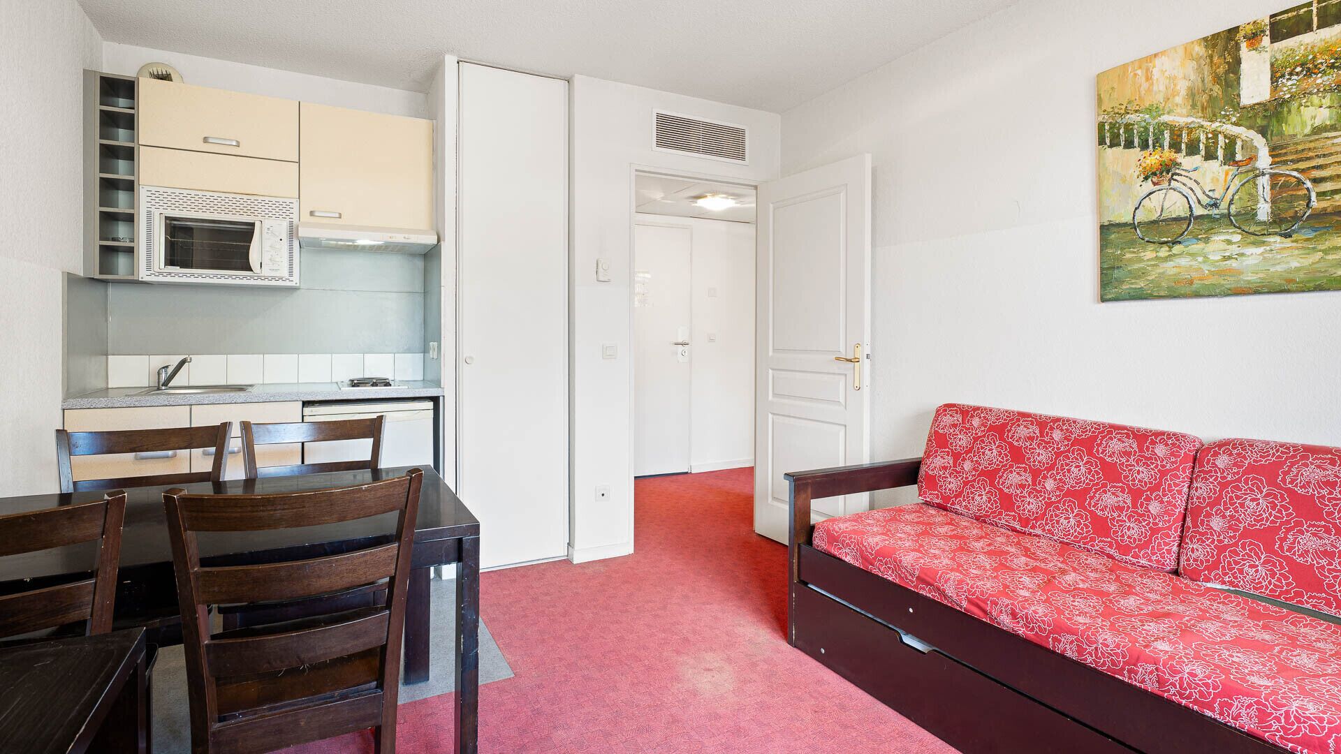 Un espacio habitable compacto con kitchenette, comedor y sofá.