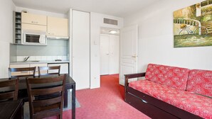 Ein kompakter Wohnbereich mit Küchenzeile, Essbereich und einer Couch.