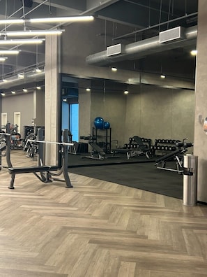 A gym with exercise equipment, wooden flooring, and a large mirror. - Millenium Luxury | Cozy Studio in Vila Olímpia (São Paulo)