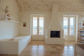 Ein modernes Wohnzimmer mit Kamin, weißen Wänden und Steinboden.