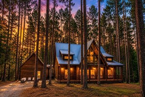 A cabin with a metal roof, wooden walls, and a porch with seating. - Luxury Group Cabin with Hot Tub & Media Room in Broken Bow, OK (Broken Bow)