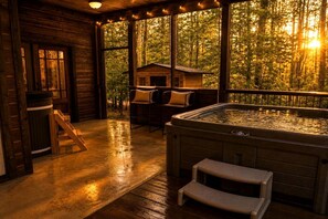 Eine Holzhütte mit Whirlpool, einer Holzterrasse und Blick auf den Wald.