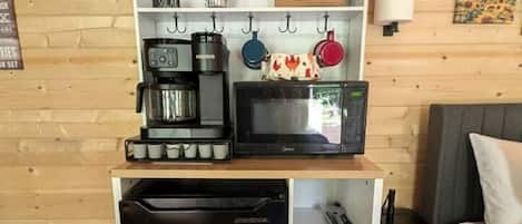 Una cuina compacta amb cafetera, microones i nevera petita.