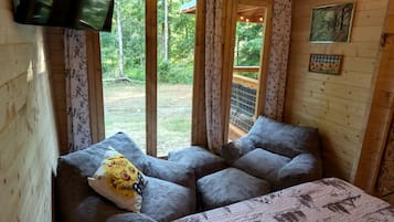 A wooden cabin with a cozy seating area featuring two sofas and a patterned bedspread.