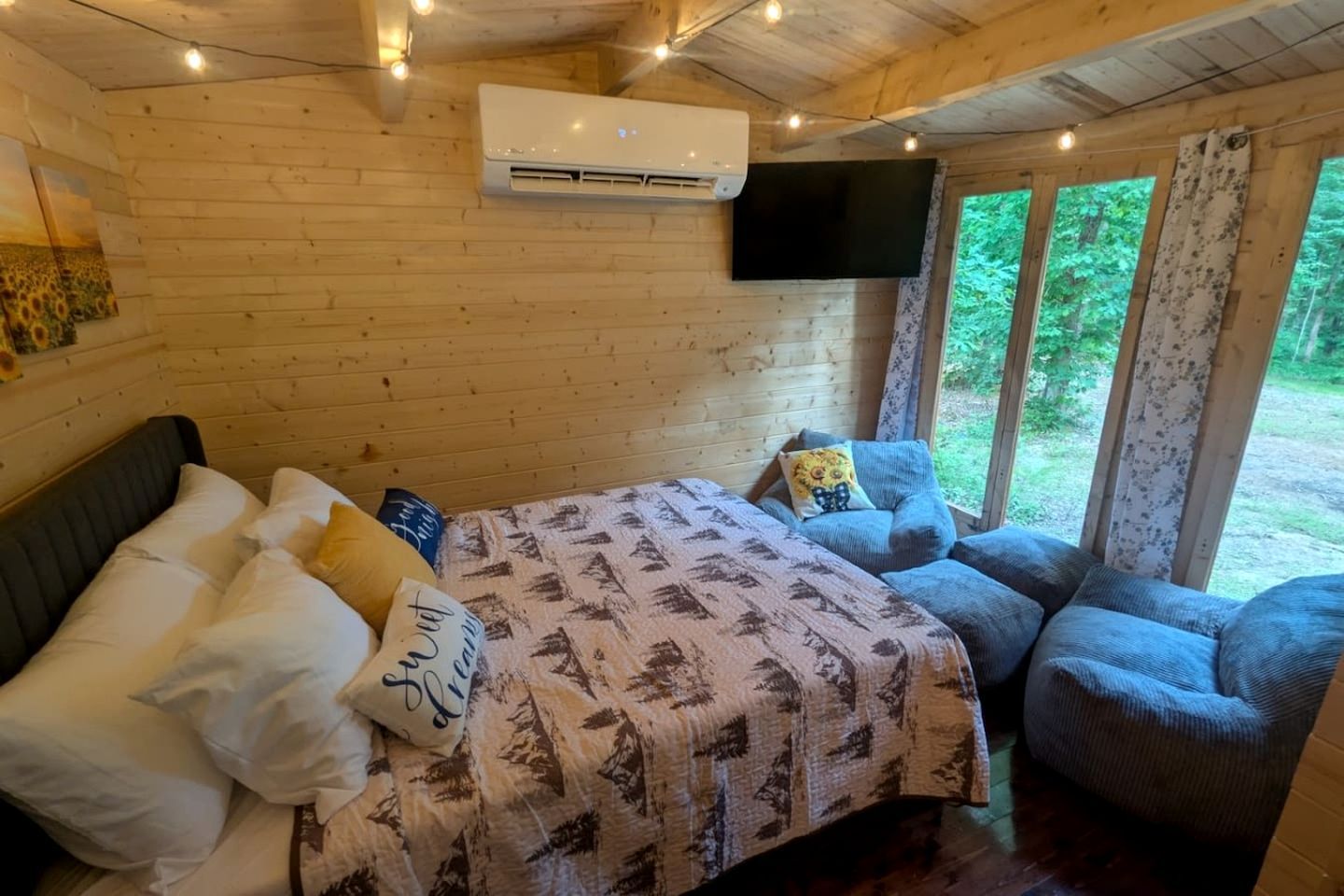 Een slaapkamer in een houten chalet met een bed, een stoel, een televisie en een airconditioner.