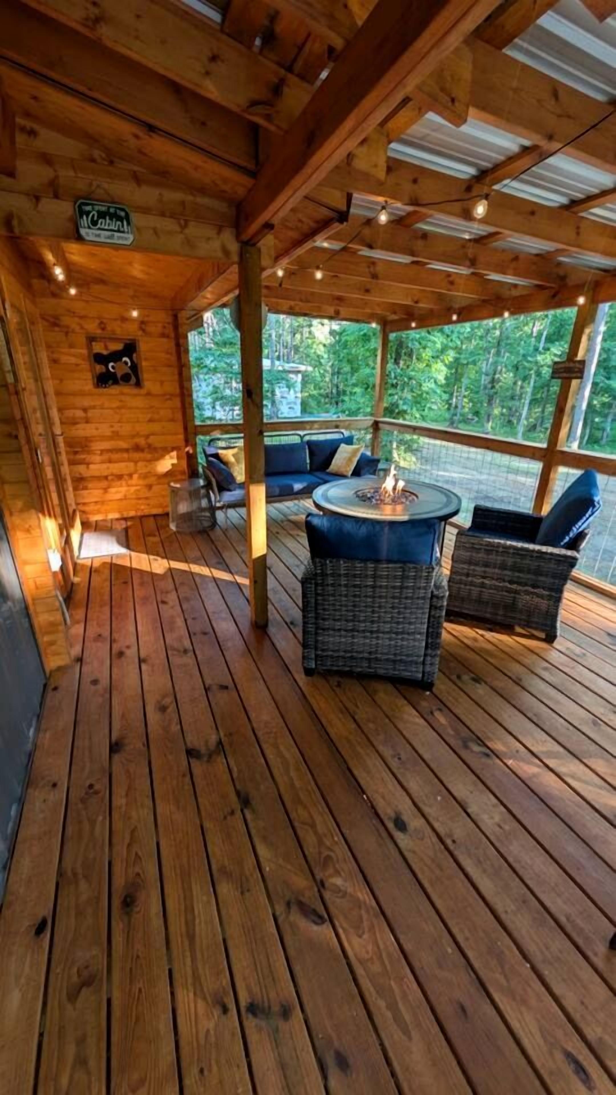 Een houten terras met rieten meubels, een vuurkorf en een bord waarop 'McCabin' staat.