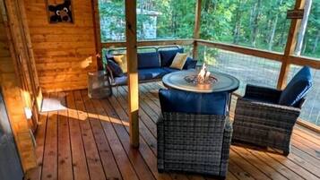Een houten terras met rieten meubels, een vuurkorf en een bord waarop 'McCabin' staat.