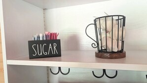 A shelf with a 'SUGAR' sign, a metal cup holder, and a black container. - Luxury Woodland Cabin Near The Caverns & Savage Gulf, Tennessee (Coalmont)