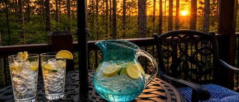A table with two glasses and a pitcher, set outdoors with a forest background.