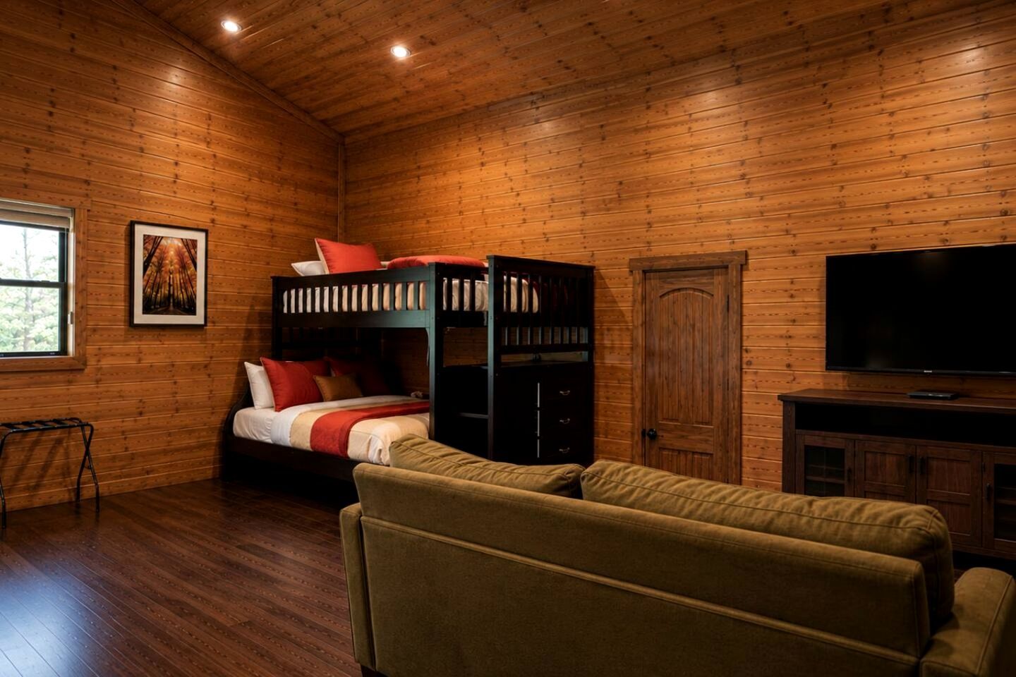 A wooden-paneled room with a bunk bed, a television, and a sofa.