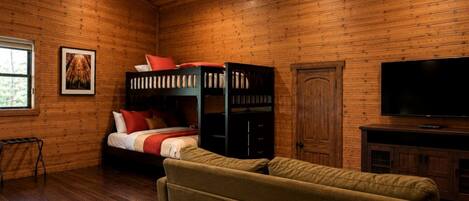 A wooden-paneled room with a bunk bed, a television, and a sofa.
