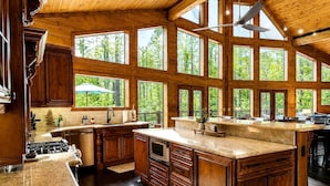 A spacious kitchen with large windows, wooden cabinetry, and a central island. - Luxury Trailside Cabin with Hot Tub near Glover River in Broken Bow, Oklahoma (Broken Bow)