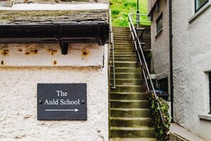 Un cartel de The Auld School con una escalera que lleva a un edificio.