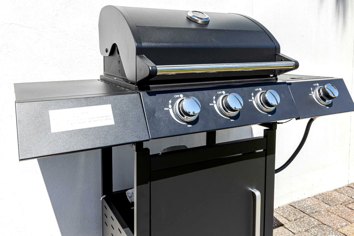 Ein tragbarer Gasgrill mit vier Kochfeldern und einem Seitenschrank.