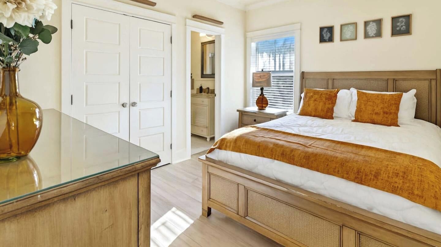 Un dormitorio con una cama grande, una mesita de noche, un aparador y una puerta.