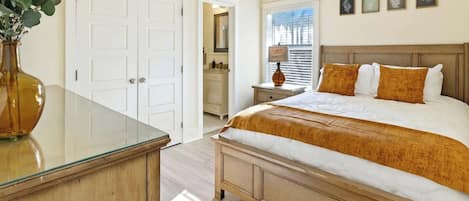Un dormitorio con una cama grande, una mesita de noche, un aparador y una puerta.