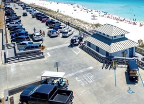 A parking lot with cars and a building with a blue roof. - Stylish Coastal Home with Private Pool & Golf Cart, Steps from Beach near Miramar Beach, Florida (Miramar Beach)